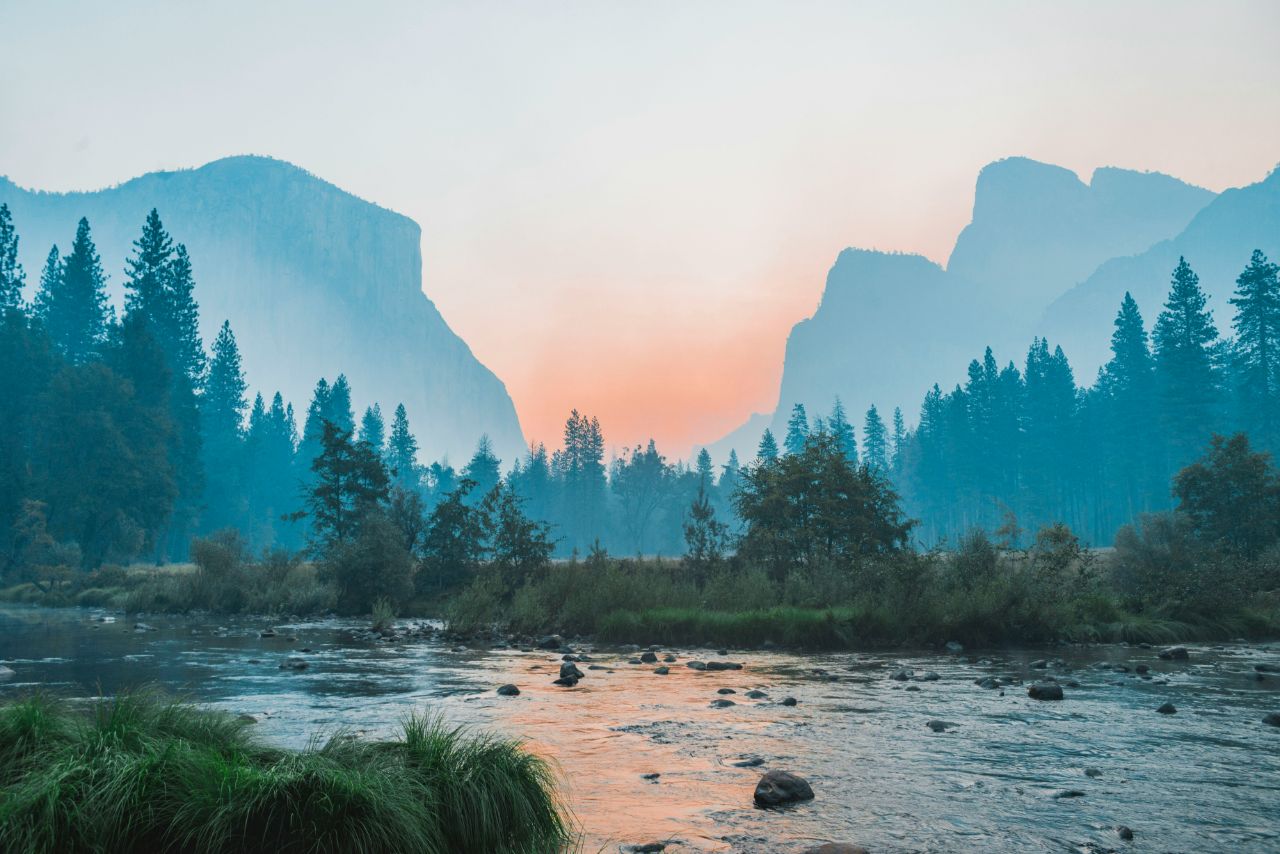 a river with trees and mountains in the background