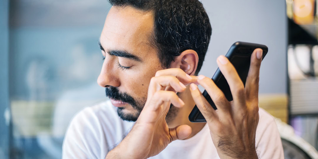 Mann mit geschlossenen Augen hält Smartphone ans Ohr