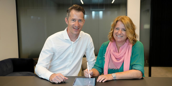 Bart Michiels (Interflex) et Kathleen Clappaert (EASYPAY GROUP) assis à un bureau signant le contrat sur une tablette