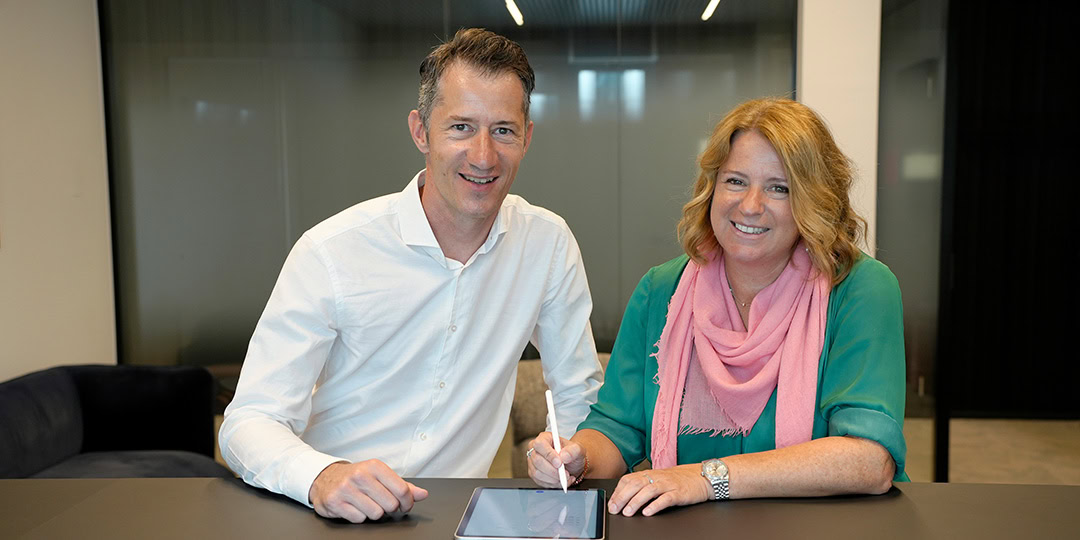 Bart Michiels (Interflex) et Kathleen Clappaert (EASYPAY GROUP) assis à un bureau signant le contrat sur une tablette