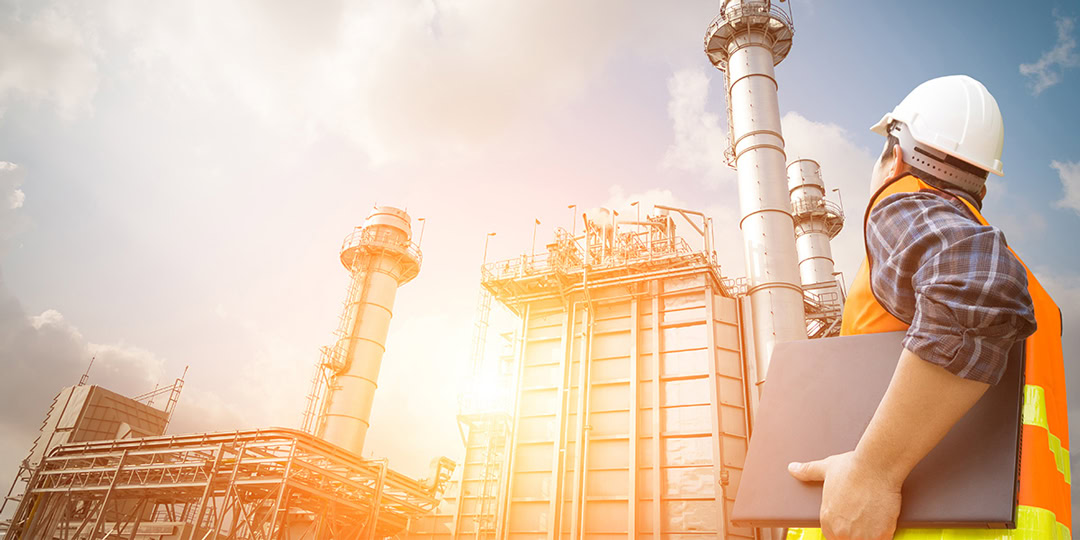 Man op bouwterrein met beveiligingshelm op kijkt naar de fabriek