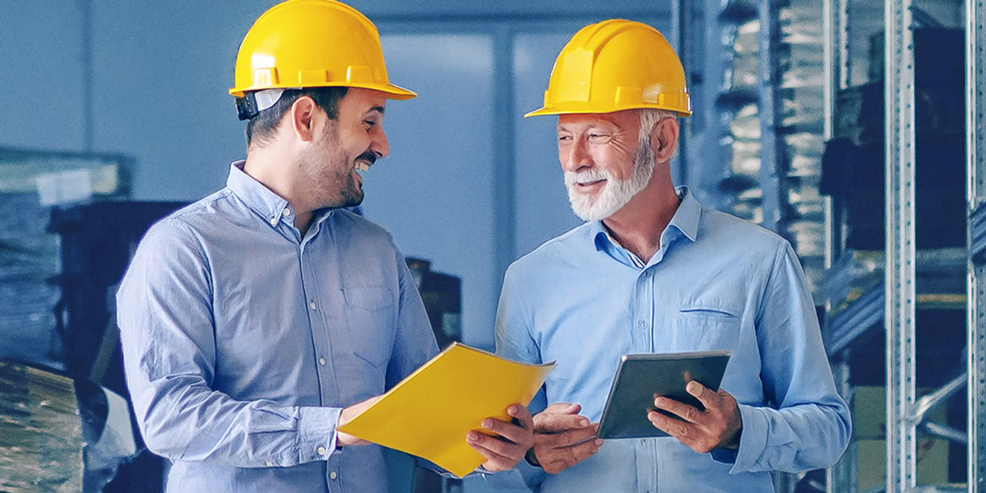 Zwei Männer mit Schutzhelm unterhalten sich lächelnd über das Modul Kostenmanagement von Interflex