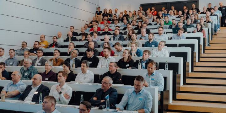 People in a modern lecture hall attentively follow a presentation.