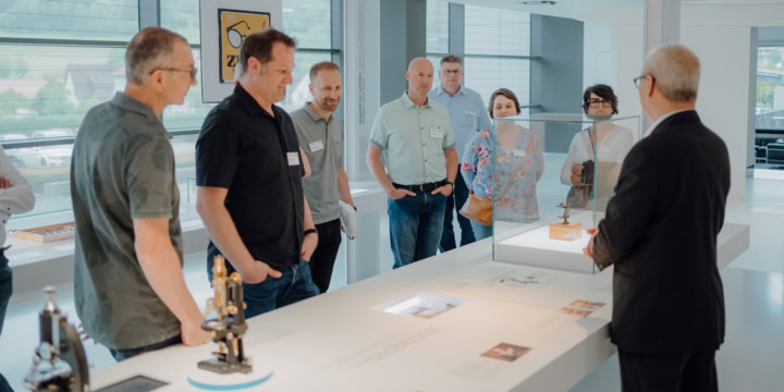 A group of people participates in a company tour at Carl Zeiss