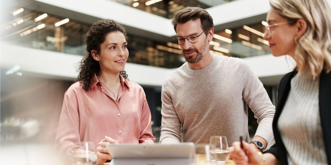 Un groupe de personnes en conversation à une table haute dans un immeuble de bureaux moderne