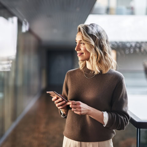 Frau hält lächelnd Smartphone in den Händen