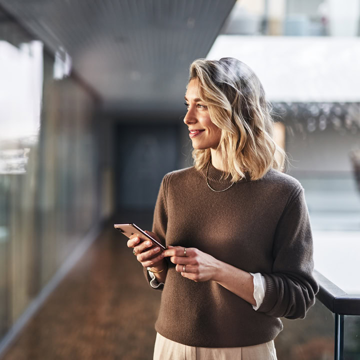 Frau hält lächelnd Smartphone in den Händen
