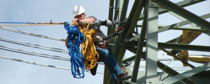 Werknemer met veiligheidshelm voert onderhoudswerkzaamheden uit aan een hoogspanningsmast
