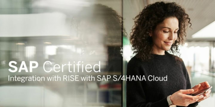 A woman leans against a glass wall in the office building and smiles at her smartphone.