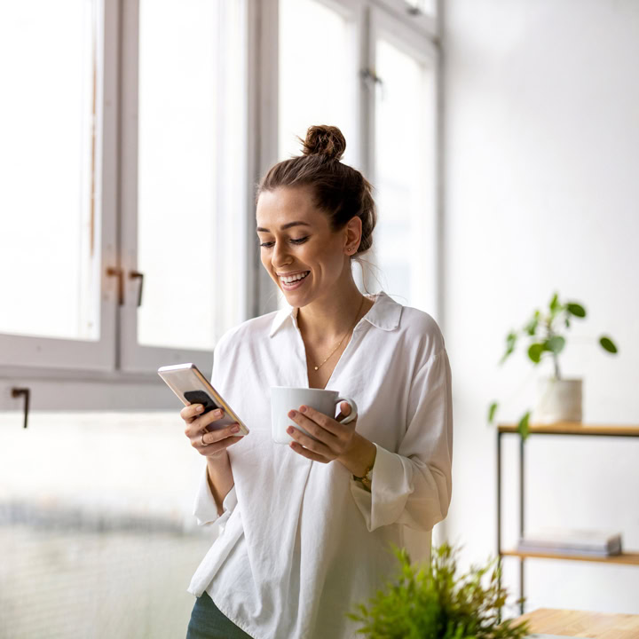 Frau blickt lächelnd auf Smartphone