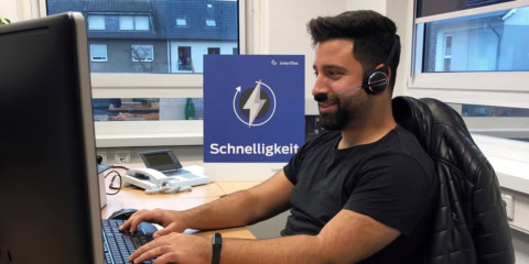 Interflex-Service-Mitarbeiter mit Headset am Schreibtisch